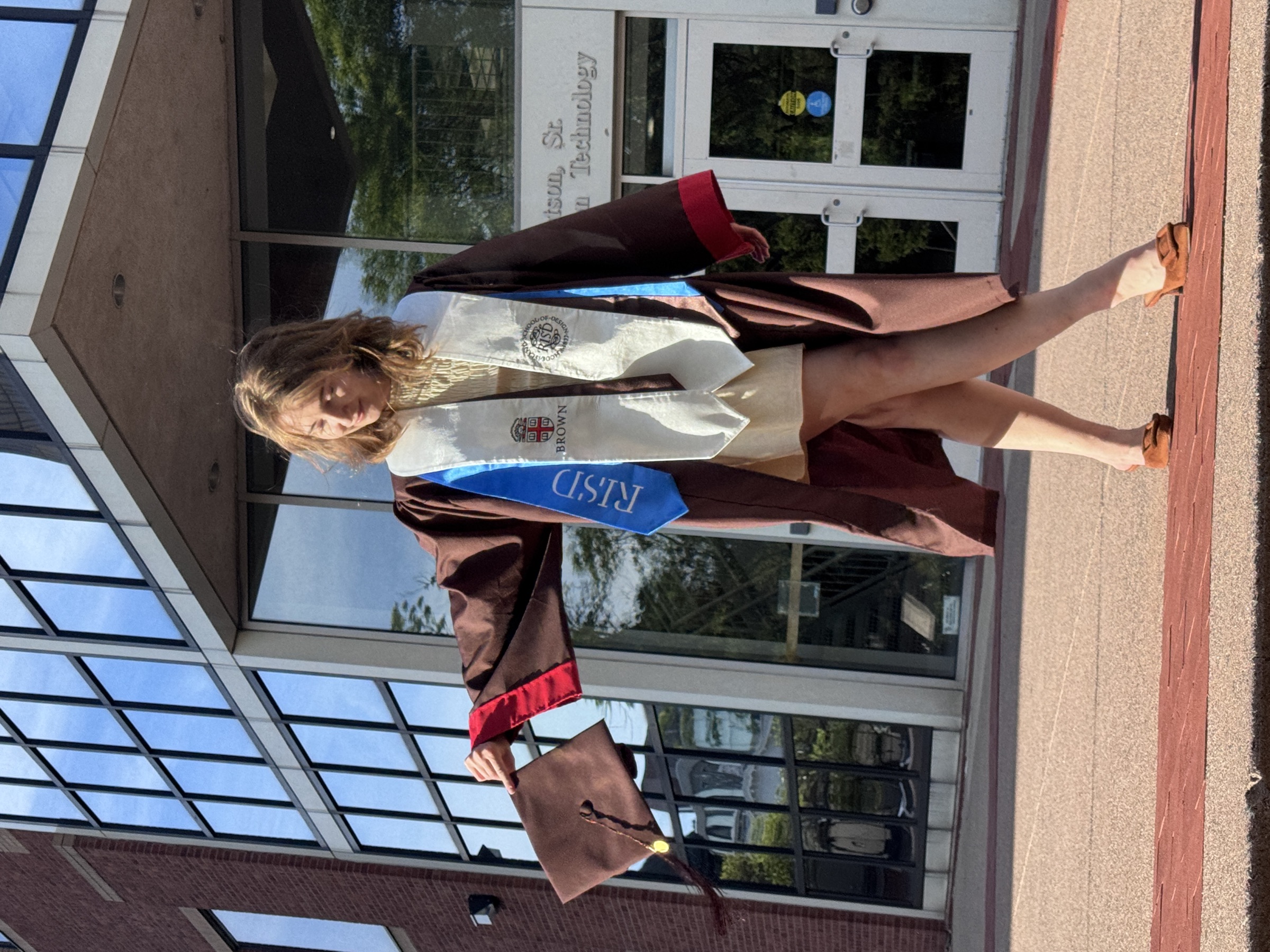 Alex posing in her graduation regalia in front of the Brown University Computer Science building